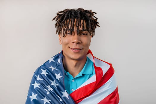 Happy african man with national USA flag on studio white background. American patriot, 4th of July - Independence day celebration, election, America, labor. US banner. High quality