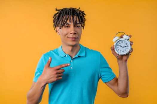 Happy schoolboy teenager with alarm clock on yellow background. Morning, correct day routine, living in moment, appreciate every minute of life, youth. High quality photo