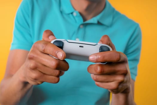 Young man playing video exciting game on Tv with joystick isolated on yellow studio background. Using modern technology.