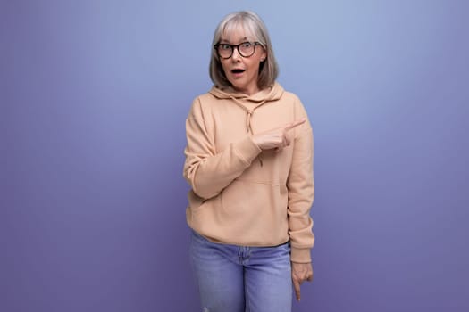 portrait of a surprised middle-aged woman in a sweatshirt on a studio background with copy space.