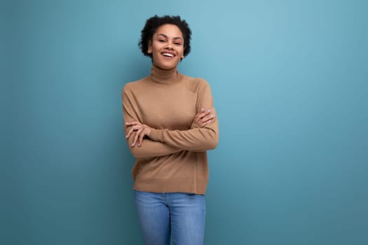 positive young bright latino woman with afro hair gathered in a ponytail against the background with copy space.