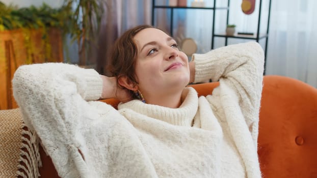 Portrait of tired young woman enjoy relaxing on home couch in room. Happy pretty girl lying on couch resting napping after hard working day, closed her eyes, put hands behind head, stress free, rest