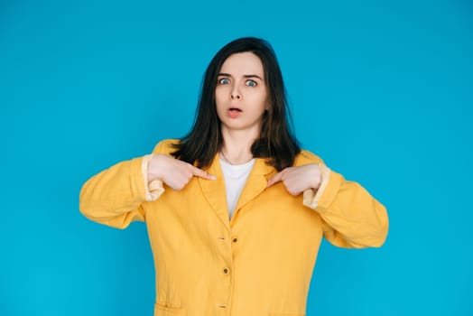 Young Frustrated University Student Pointing Fingers at Herself, Feeling Unhappy and Angry - Exam Stress, Forgetfulness, Isolated on Blue Background.