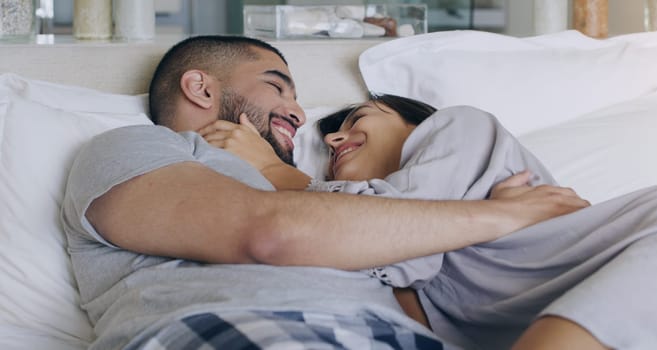 Couple, love and smile in bed, bonding and romance of intimacy, special moment and trust together at home. Happy young man, woman and partner in relationship, honeymoon and relax for care in bedroom.