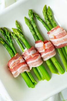 Green asparagus baked with bacon and spices. Very tasty and healthy food. View from above. Vertical photo