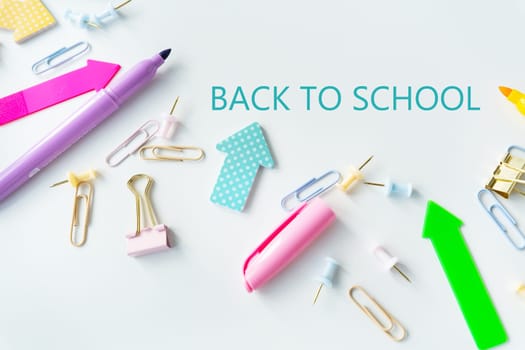 Top view of bright colored school supplies with blank paper and back to school lettering