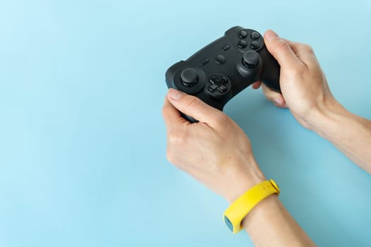 Isolated hands on a blue background that hold a joystick. Young gamer, game, recreation, competition
