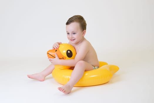 adorable boy sitting on a duck float on a white background. Summer Vacation.