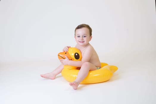 adorable boy sitting on a duck float on a white background. Summer Vacation.