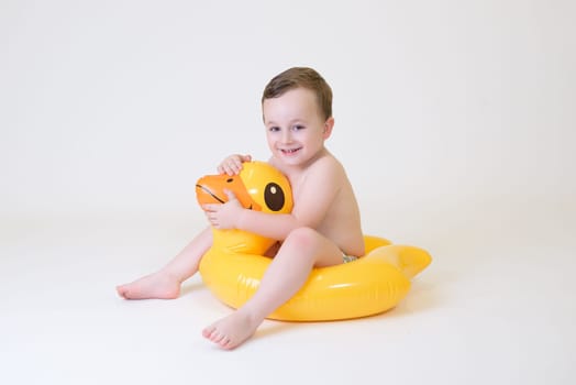 adorable boy sitting on a duck float on a white background. Summer Vacation.