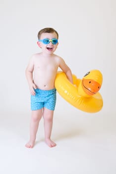 cute boy with inflatable float and diving goggles on white background.