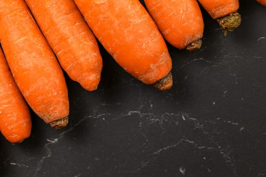 Top down view, detail of carrots on black board, space for text in down right corner.