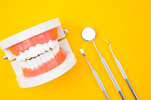 Dentures model and instrument dental on yellow background.