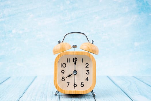 Wooden vintage alarm clock on blue wooden floor.