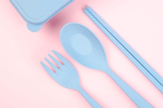 Blue Plastic spoons, forks and chopsticks set on pink color background.
