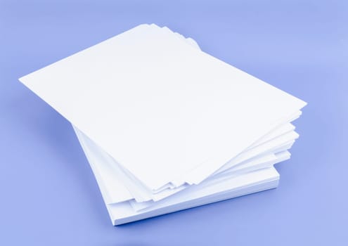 Stack of blank A4 paper sheets on blue background.