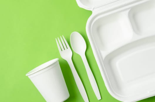 Eco friendly biodegradable paper disposable for packaging food and paper glass on green background.