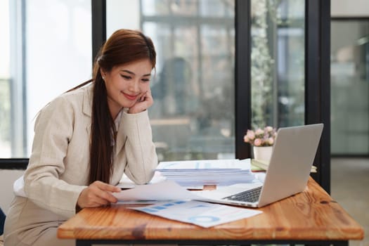 Asian Business person makes analysis and research financial report at office, analyzes profits. Accountant checks status of financial.