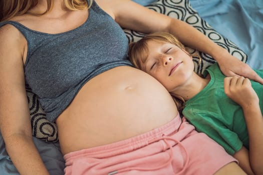 Young beautiful pregnant woman and eldest son. The cute boy leaned his ear against his mother's belly. Expecting a baby in the family concept. Preparing an older child for a younger one.