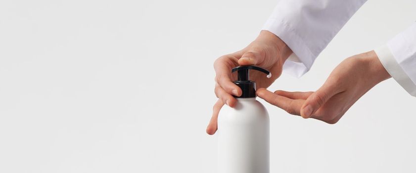 Woman hands pushing pump plastic soap bottle on white background