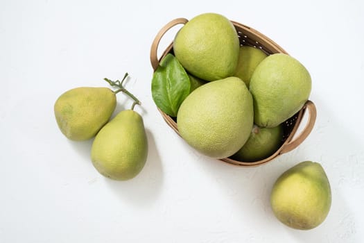 Fresh pomelo, pummelo, grapefruit, shaddock on white cement background in bamboo basket. Autumn seasonal fruit, top view, flat lay, tabletop shot.