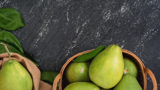 Fresh peeled pomelo, pummelo, grapefruit, shaddock on dark background in bamboo basket. Autumn seasonal fruit, top view, flat lay, tabletop shot.