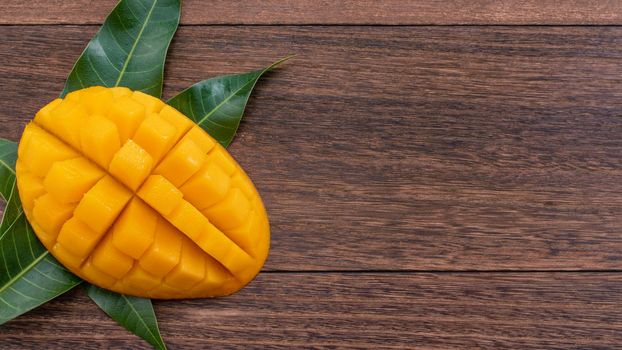 Fresh mango,beautiful chopped fruit with green leaves on dark wooden table background. Tropical fruit design concept. Flat lay. Top view. Copy space