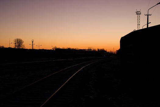 Railroad rails in the snow in the dark at dawn