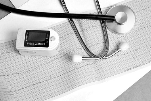 One pulse oximeter and stethoscope on a blue background, back and white