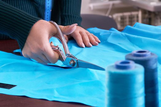 Dressmaker cutting fabric in atelier shop