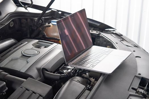 Services car engine machine concept, Automobile mechanic repairman checking a car engine with using computer diagnostics while repairing, car service and maintenance.