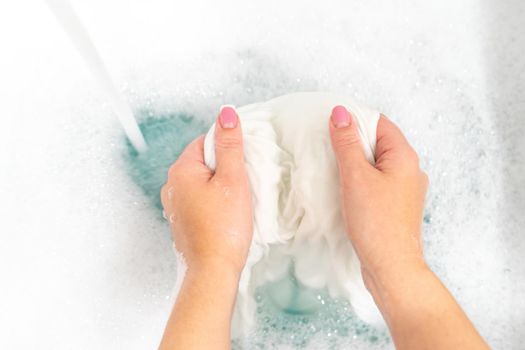 Female hands washing color clothes in basin