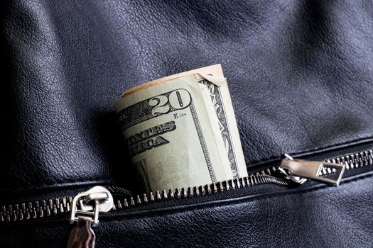 Dollars in the pocket of a black leather bag close up