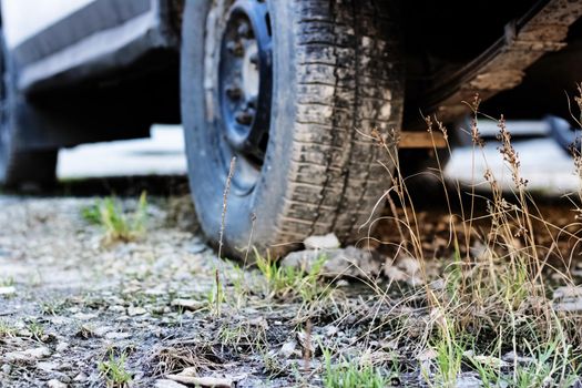 Stone under a car wheel in the grass close up