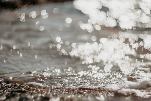 Abstract nature summer or spring ocean sea background. Small waves on water surface in motion blur with bokeh lights from sunrise.