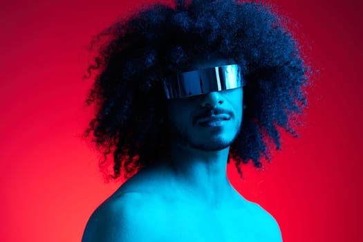 Portrait of fashion man with curly hair on red background with stylish glasses, multinational, colored light, black leather jacket trend, modern concept, sexy body. High quality photo