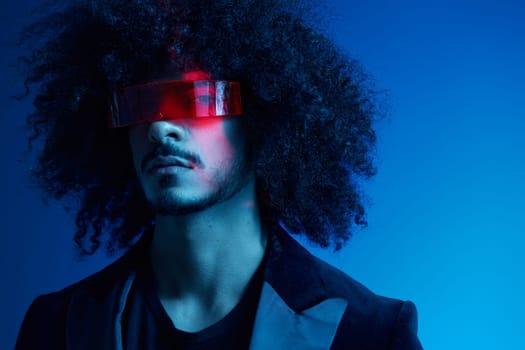 Fashion portrait of a man with curly hair on a blue background wearing red sunglasses, multinational, colored light, trendy, modern concept. High quality photo