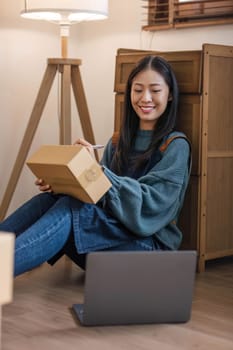 Happy young Asian woman entrepreneur, Smile for sales success after checking order from online shopping store in a laptop at home office, Concept of merchant business online and eCommerce..