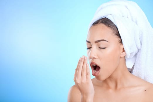 Shower, grooming and woman smelling breath for oral care isolated on blue background in a studio. Dental, healthcare and girl breathing into hand to check for odor problem on a mockup space backdrop.