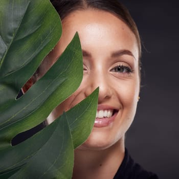 Beauty, skin and face with leaf and woman, skincare with nature aesthetic, natural cosmetics and facial portrait against studio background. Smile, glow with organic cosmetic treatment and wellness