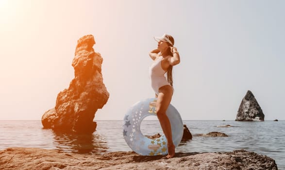 Woman summer sea. Happy woman swimming with inflatable donut on the beach in summer sunny day, surrounded by volcanic mountains. Summer vacation concept