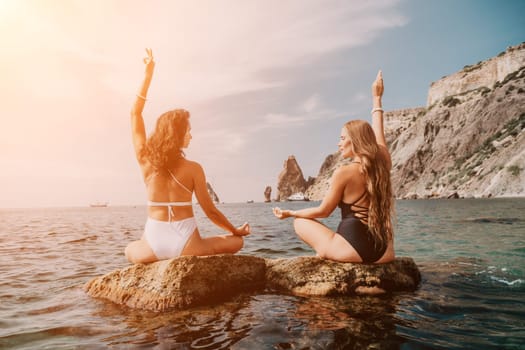 Woman sea yoga. Back view of free calm happy satisfied woman with long hair standing on top rock with yoga position against of sky by the sea. Healthy lifestyle outdoors in nature, fitness concept.