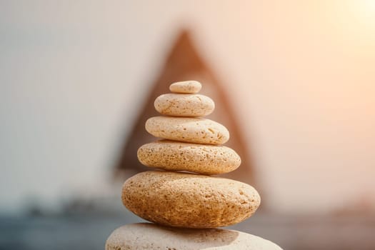 Pyramid stones on the seashore with warm sunset on the sea background. Happy holidays. Pebble beach, calm sea, travel destination. Concept of happy vacation on the sea, meditation, spa, calmness.