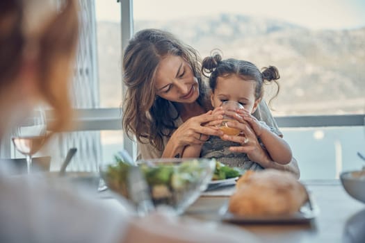 Mother, baby at lunch and drinking juice with family at dining room patio table, by the sea and on holiday. Girl child, loving mom and people bonding with food at seaside summer house for vacation.