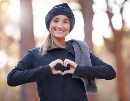 Portrait, heart hands and smile of woman hiking outdoors for wellness and fitness. Valentines day, love emoji and happy female with hand gesture for romance affection, support or empathy in winter