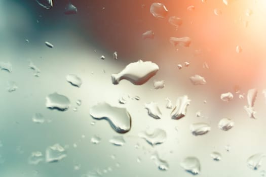 Raindrops on glass against blue sky. Window view background screensaver. Place for text banner.