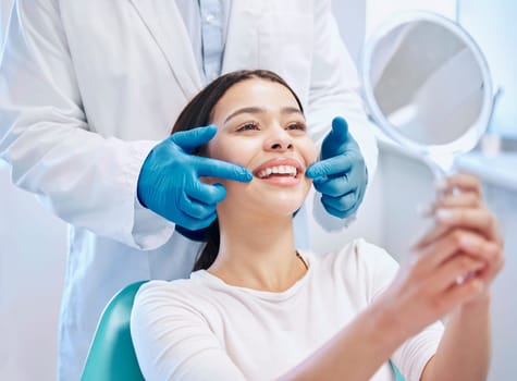 Dental consultation, mirror and woman with smile after teeth whitening, service or mouth care. Healthcare, dentistry and happy female patient with orthodontist for oral hygiene, wellness and cleaning.