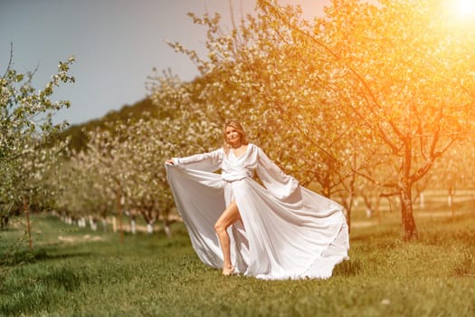 Woman white dress park. A woman in a white dress runs through a blossoming cherry orchard. The long dress flies to the sides, the bride runs rejoicing in life