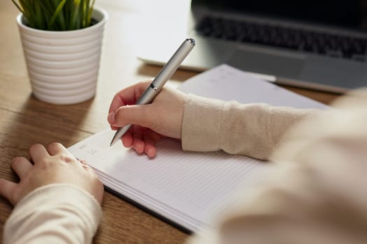 Businessman writes with a pen in diary in a sunny office, business and education concept. Close up