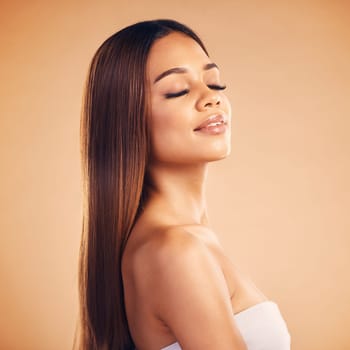 Beauty, hair and face of woman for wellness, keratin treatment and cosmetics in studio. Salon, hairdresser and female person with eyes closed on orange background for growth, hairstyle and texture.